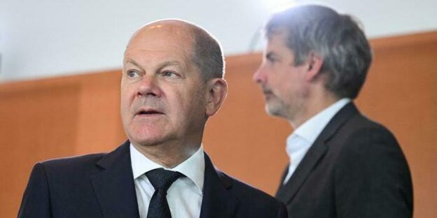 Bundeskanzler Olaf Scholz, im Hintergrund ist von der Seite sein Sprecher Steffen Hebestreit zu sehen