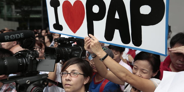 Anhänger der People's Action Party in Singapur mit „I love PAP“-Schild