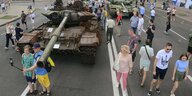 Menschen zwischen ausgestellten zerstörten Panzern