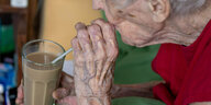 Eine alte Frau trinkt mit einem Strohhalm.