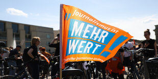 „Journalismus ist Mehrwert / mehr wert“ steht auf einer Fahne bei einer Demonstration von Mitarbeitern der Deutschen Welle auf dem Pariser Platz. Sie demonstrieren gegen Sparpläne ihres Arbeitgebers