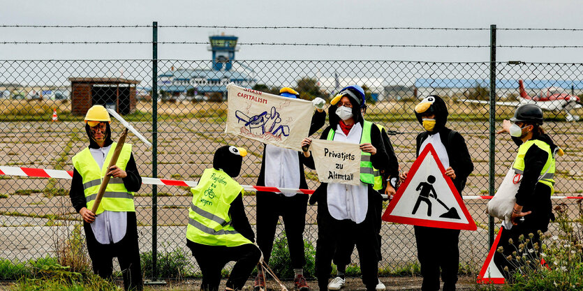 Verkleidete Aktivist:innen vor einem Flughafen.