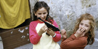 Zwei Mädchen spielen lachend mit einer Pistole
