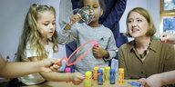 Lisa Paus sitzt mit Kindern an einem Tisch und spielt mit Seifenblasen