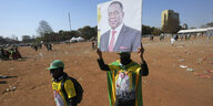Zwei Männer mit breitem Lächeln und in den gelb-grünen Farben der Regierungspartei Zanu-PF, einer hält ein Porträt des wiedergewählten Präsidenten Mnangagwa hoch
