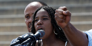 Eine junge Schwarze Frau spricht in ein Mikrophon