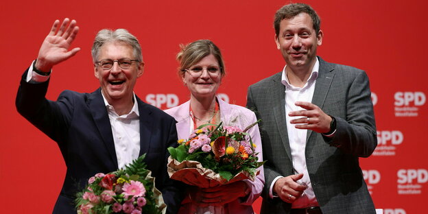 Lars Klingbeil (rechts) mit der neuen Doppelspitze der NRW-SPD. Links steht Achim Post, in der Mitte steht Sarah Philipp, die beide einen Blumenstrauß in der Hand halten