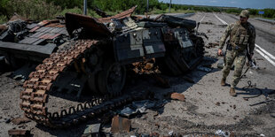 Ein ukrainischem Soldat steht neben seinem zerstörten Panzer