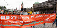Demonstrierende halten an den Hamburger Landungsbrücken ein Transparent mit der Aufschrift «Seenotrettung ist Unverhandelbar - Free movement for all».
