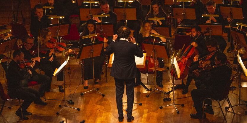 Der Dirigent des Kyiv Symphony Orchestra steht mit dem Rücken zum Publikum und dirigiert die Musik zu "Metropolis", vor ihm das Orchester