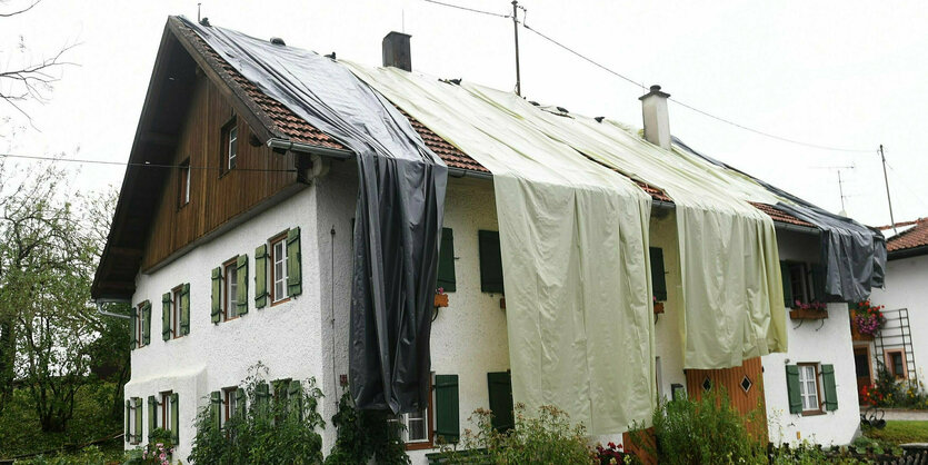 Nach dem Unwetter ist das Dach eines Wohnhauses mit Planen provisorisch abgedeckt.