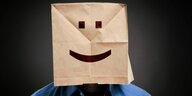 Ein Mann mit Smiley-Papiertüte auf dem Kopf