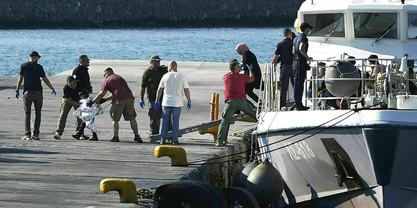 Gerettete Migranten, darunter auch ein kleines Kind, verlassen ein Schiff der Küstenwache