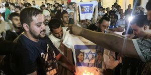 Menschen verbrennen ein T-Shirt mit dem Bild des israelischen Außenministers Eli Cohen und seiner libyschen Amtskollegin Najla Mangoush in Tripolis