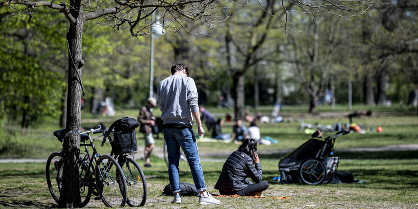 Menschen stehen und sitzen auf einer Wiese in der Hasenheide