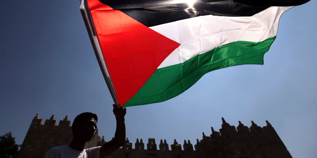 Ein Mann schwenkt eine palästinensische Fahne in Jerusalem
