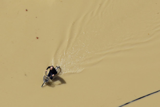 Ein Mann fährt mit dem Rad durch eine überflutete Straße