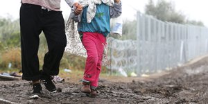 Ein Mann und ein Kind überqueren die serbisch-ungarische Grenze.