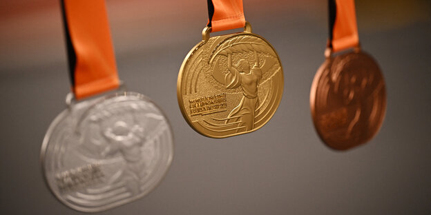 Drei Medaillen, silber, gold und bronze an roten Bändern