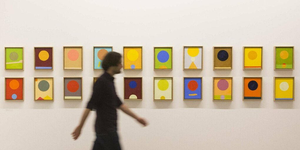 Ein Museumsbesucher läuft an den Kunstwerken der Künstlerin Etel Adnan vorbei.