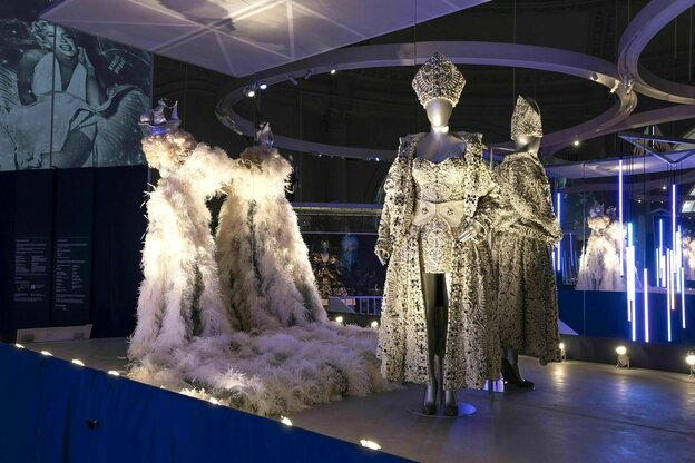 Opulente Kostüme mit Federn und Brokat an Puppen stehen im Victoria and Albert Museum