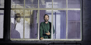 Ein Schauspieler steht an einem Fenster in einer ehemaligen Fabrikhalle, die als Veranstaltungsort genutzt wird