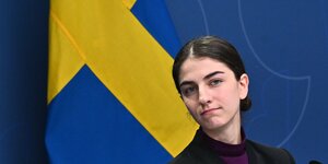 Umweltministerin Romina Pourmokhtari vor einer schwedischen Flagge.