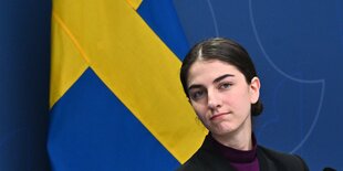 Umweltministerin Romina Pourmokhtari vor einer schwedischen Flagge.