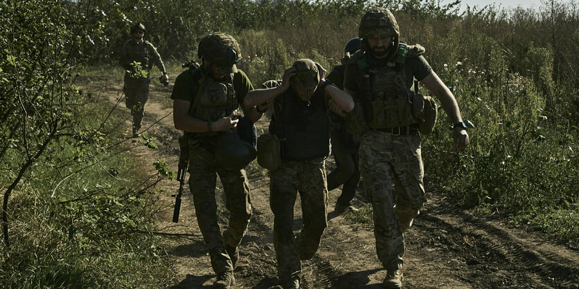 Zwei Soldaten haken einen dritten verwundeten unter