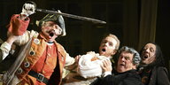 Szene aus dem Barbeir von Sevilla, maskierte Männer mit Perücken, singen, einer schwingt ein Schwert