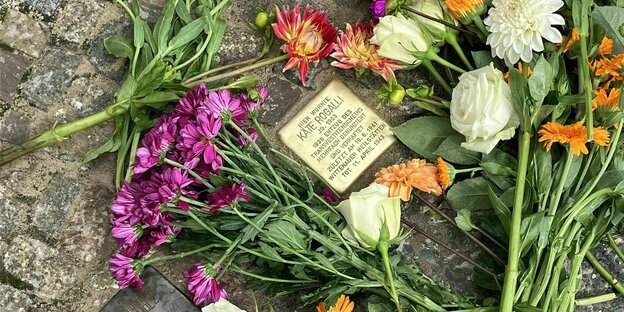 Stolperstein von Käte Rogalli, der mit bunten Blumen geschmückt ist