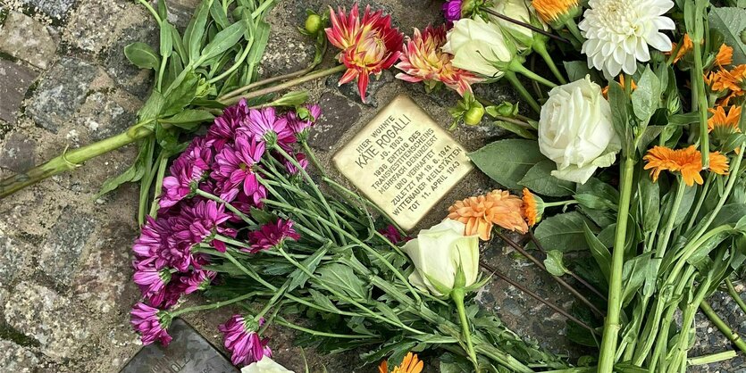 Stolperstein von Käte Rogalli, der mit bunten Blumen geschmückt ist