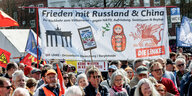 Teilnehmer des Hamburger Ostermarschs halten ein Transparent mit der Aufschrift "Frieden mit Russland und China. Für Rückkehr zum Völkerrecht, gegen NATO, Aufrüstung, Sanktionen und Boykott"