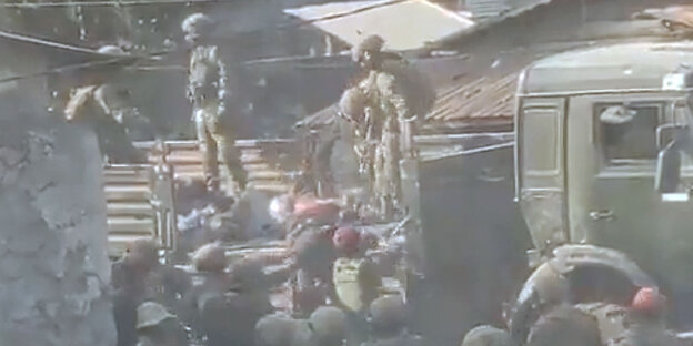 Ein Videostill zeigt Kongolesiche Soldaten, die Leichen auf einen Lastwagen schaffen