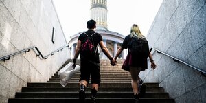 Zwei alternativ gekleidete Personen gehen eine Treppe zur Berliner Siegessäule hinauf