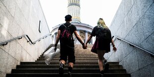 Zwei alternativ gekleidete Personen gehen eine Treppe zur Berliner Siegessäule hinauf