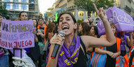 Eine Frau steht vor einer Menschenmenge und schreit in eine Mikrofon