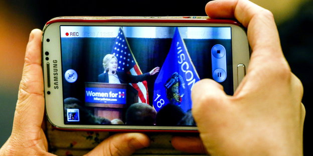 Durch die Kamera eines Smartphones ist Hillary Clinton zu sehen