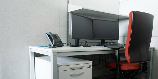roter Bürostuhl an einem Schreibtisch mit 2 Monitoren