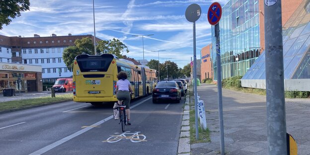 Der Radweg in der Ollenhauer Straße in Reinickendorf mit einer Radfahererin und einem Bus auf der Busspur