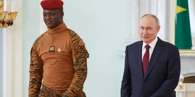 Der russische Präsident Putin (rechts) im Anzug und der Interimspräsident von Burkina Faso Traoré (links) mit roter Mütze und orangener Kleidung.