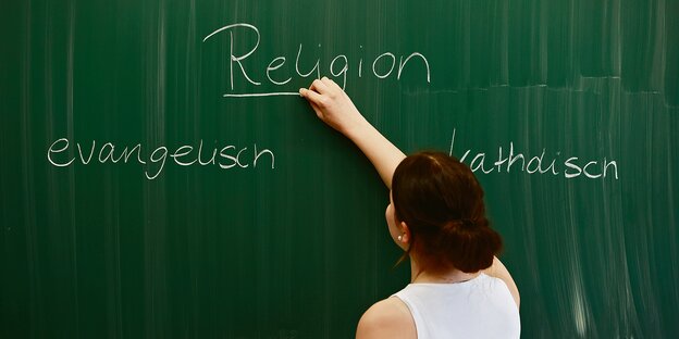 Eine Frau schreibt an eine Tafel "Religion"