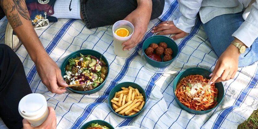 Picknick mit Mehrwegverpackungen auf einem karierten Tuch