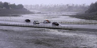 Überschwemmung einer Brücke, auf der Autos fahren