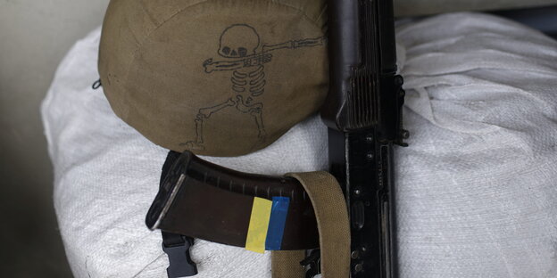 Helm mit Totenkopf und Gewehr mit den Farben der Ukraine