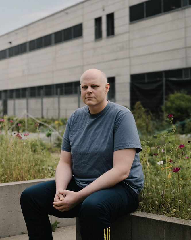 Christian Twachtmann sitzt an einem Blumenbeet in Jogginghose und T-Shirt