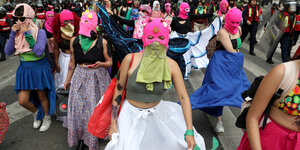 Frauen mit pinkfarbenen Sturmmützen maskiert gehen auf einer Strasse