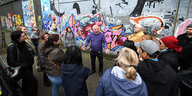 ein Touristen-Guide vor einem Mural in Belfast, umringt von einer Gruppe Menschen