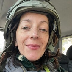 Sergatskova lächelt, trägt einen militärischen Helm und eine schusssichere Weste