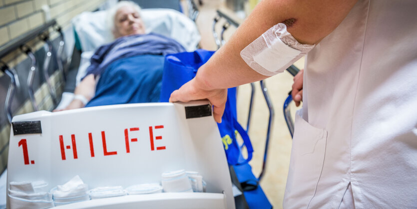 1. Hilfe steht auf dem Bett, eine Person schiebt einen Patienten